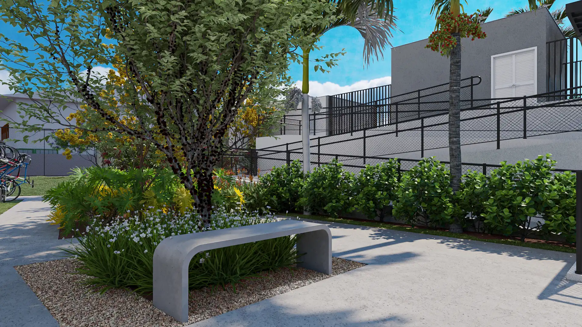 Área verde com banco de concreto, jardim e árvores floridas